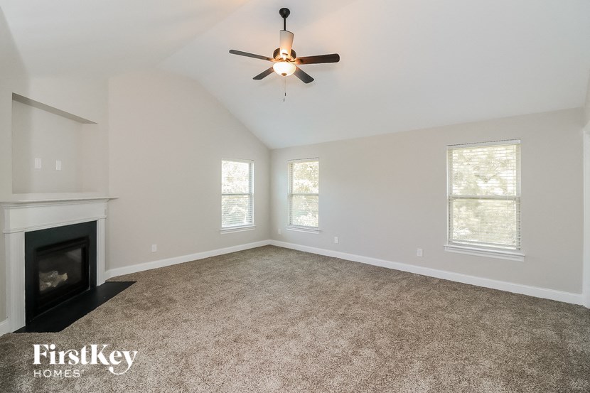 an empty living room with a fireplace and a ceiling fan