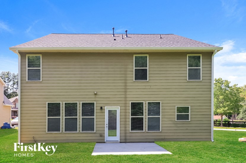 a tan house with a white front porch on a lawn