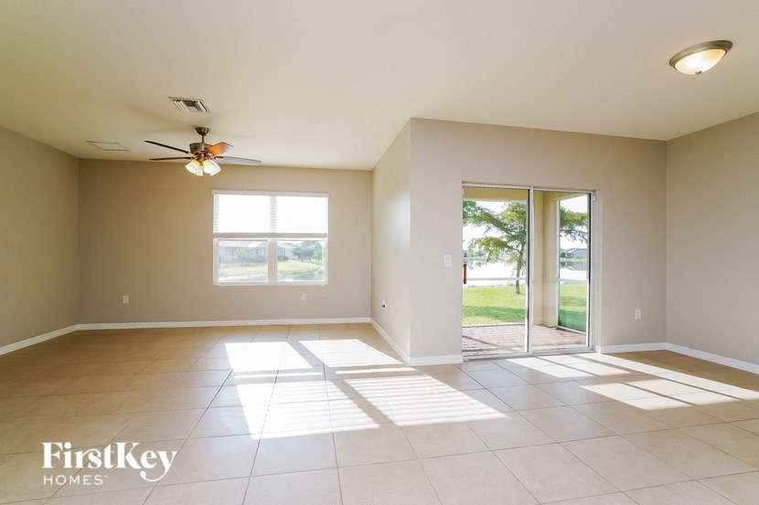 an empty living room with a ceiling fan and glass doors