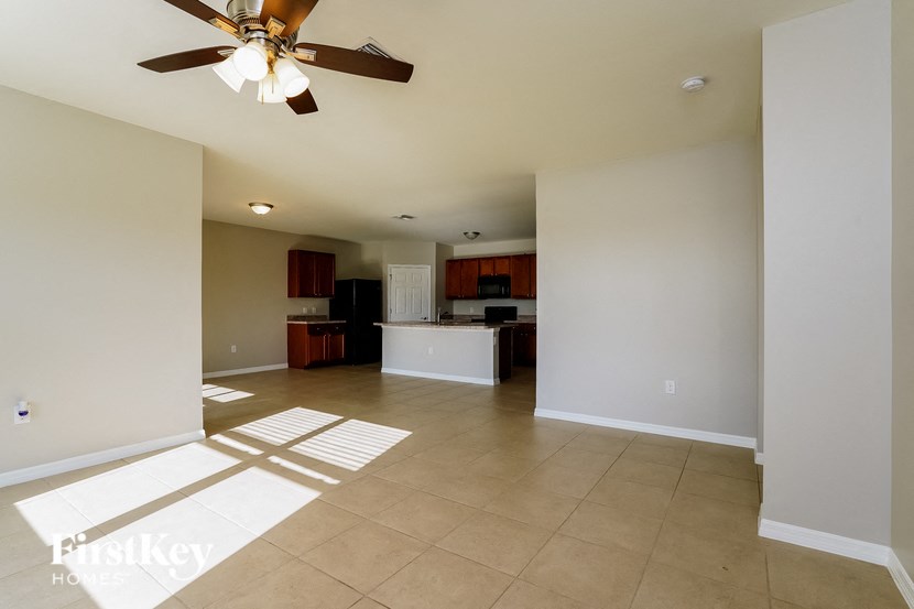 a empty living room and kitchen with a ceiling fan