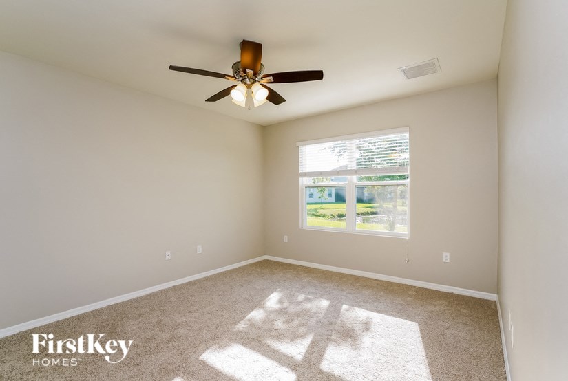 an empty living room with a ceiling fan and a window