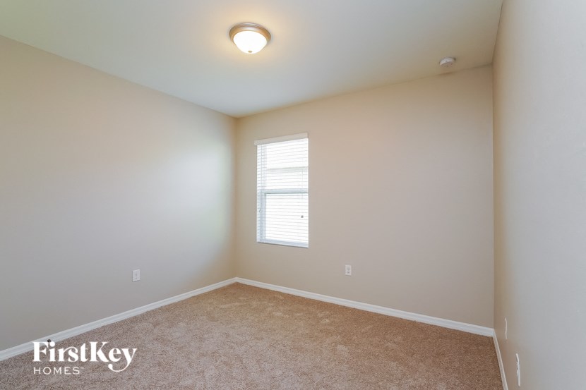 a bedroom with white walls and a window and carpet