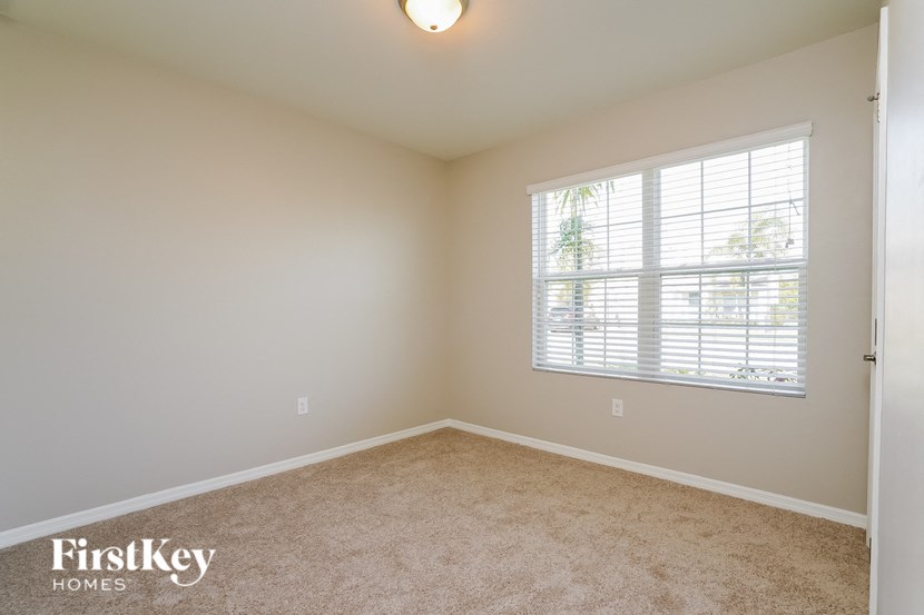 a bedroom with a large window and a carpeted floor