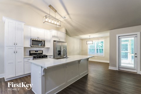 A kitchen with white cabinets and a wooden floor.
