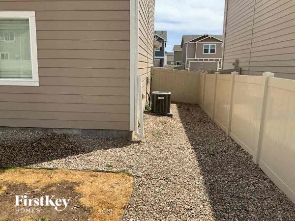 a backyard with a fence and a trash can