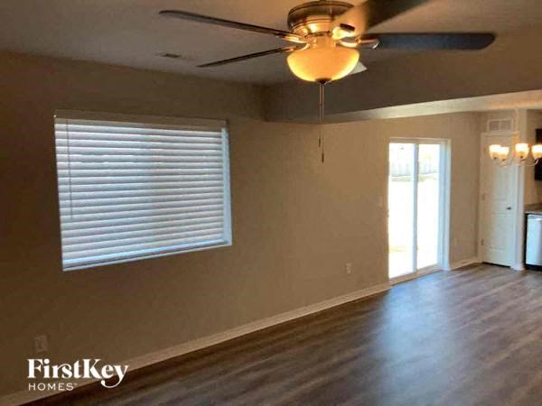 an empty living room with a ceiling fan and a window