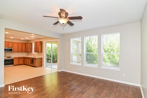 an empty living room with a ceiling fan and a kitchen