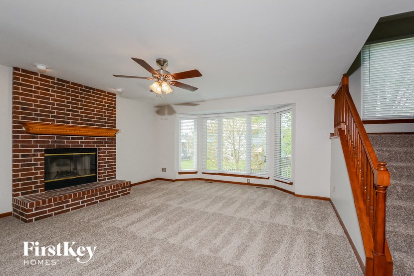 a living room with a brick fireplace and a ceiling fan