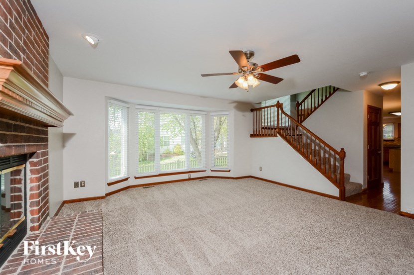 an empty living room with a fireplace and a ceiling fan
