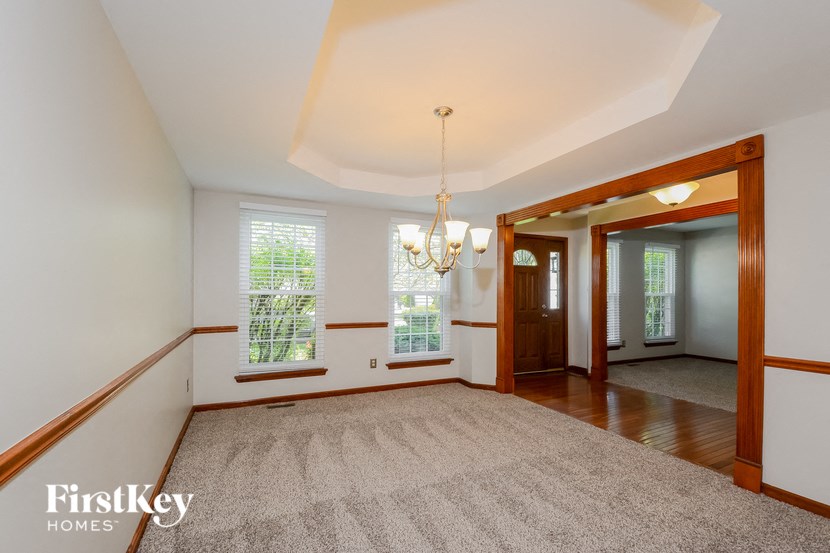 an empty dining room with a rug and a chandelier