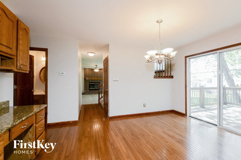 an empty living room with wood flooring and a sliding glass door to the kitchen