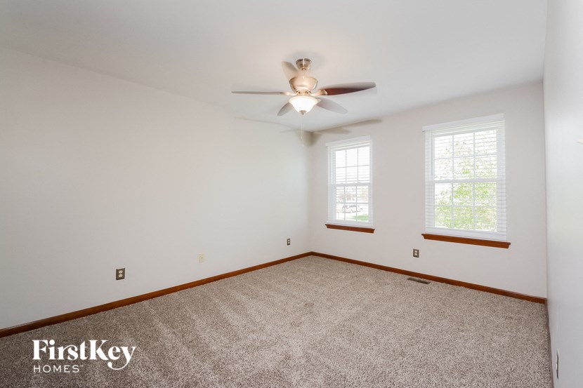 a bedroom with carpet and a ceiling fan and two windows