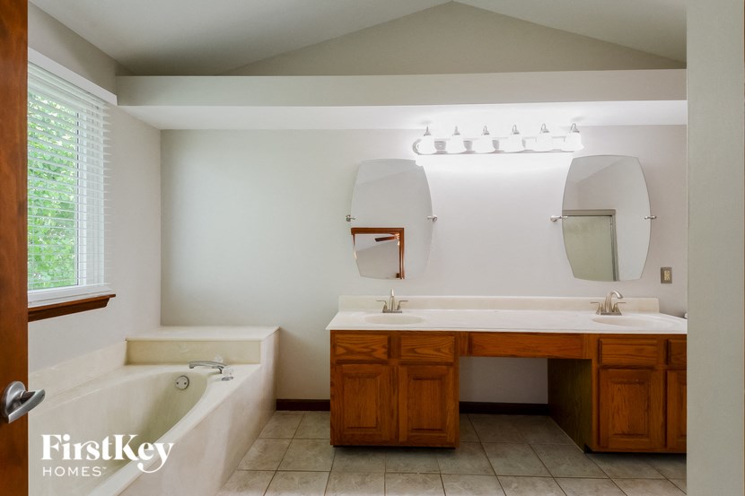 a bathroom with two sinks and a tub and two mirrors
