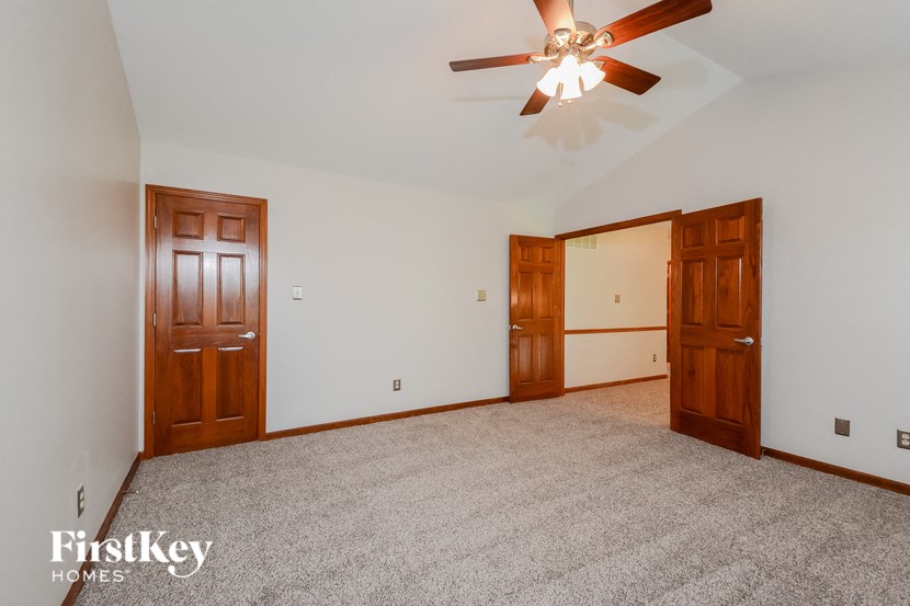 a master bedroom with carpet and a ceiling fan