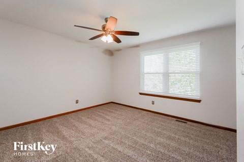 the living room of a home with a carpet and a ceiling fan