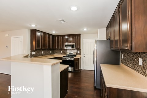 A kitchen with dark wood cabinets and a black refrigerator.