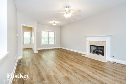 a living room with a fireplace and wooden floors and a ceiling fan
