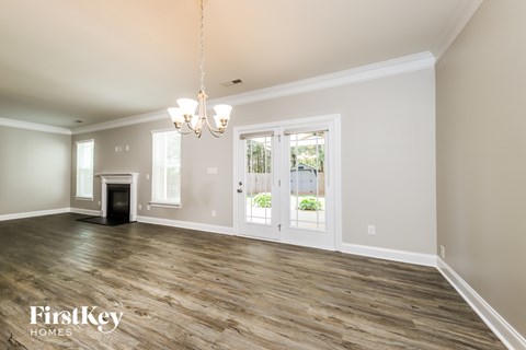 A spacious room with wood flooring and a chandelier.