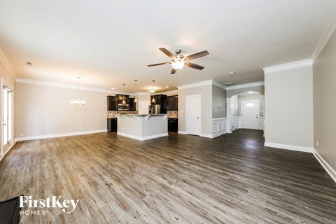 A spacious room with wooden flooring and a ceiling fan.
