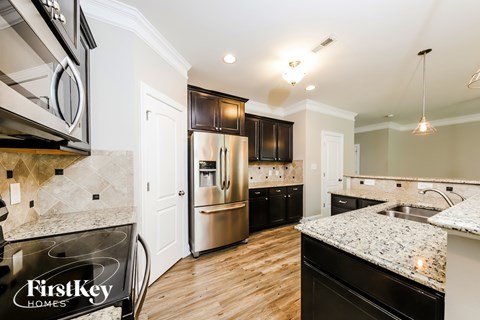 A kitchen with a granite counter top and a stainless steel refrigerator.