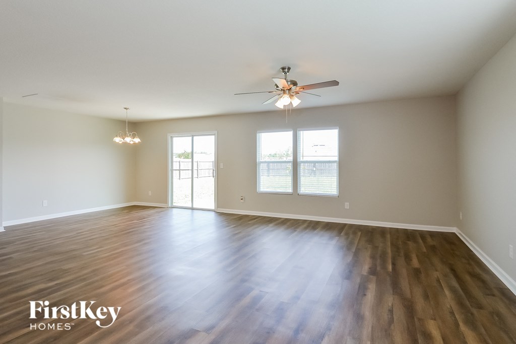 an empty living room with wood floors and a ceiling fan