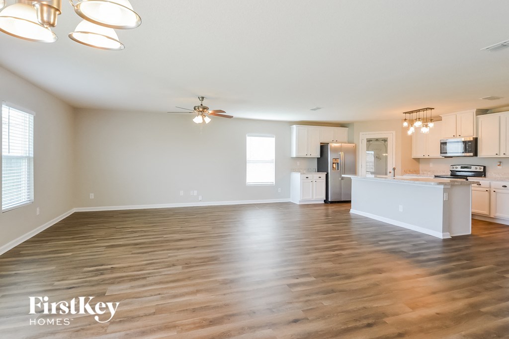 the living room and kitchen of an empty house with wood flooring