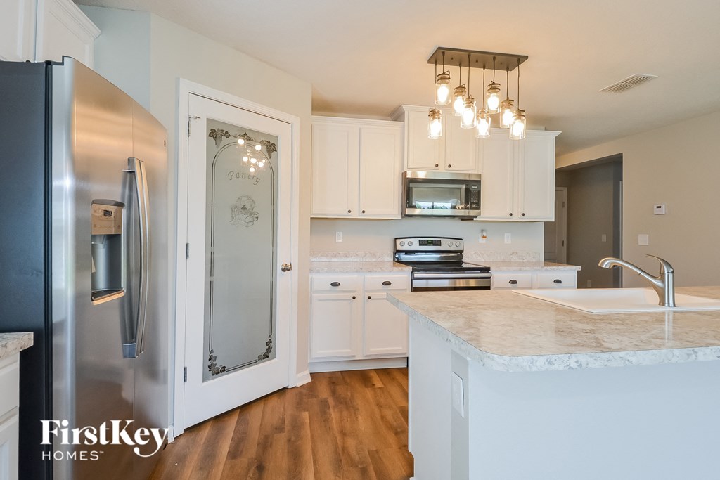 a kitchen with white cabinets and stainless steel appliances and a marble counter top