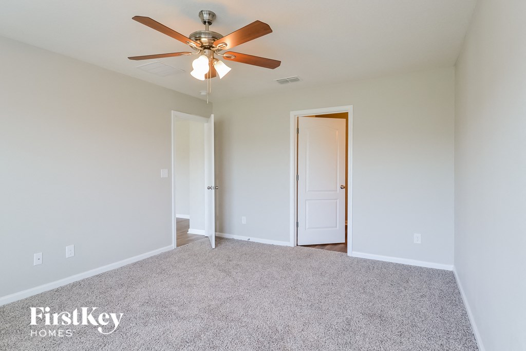 a bedroom with white carpet and a ceiling fan