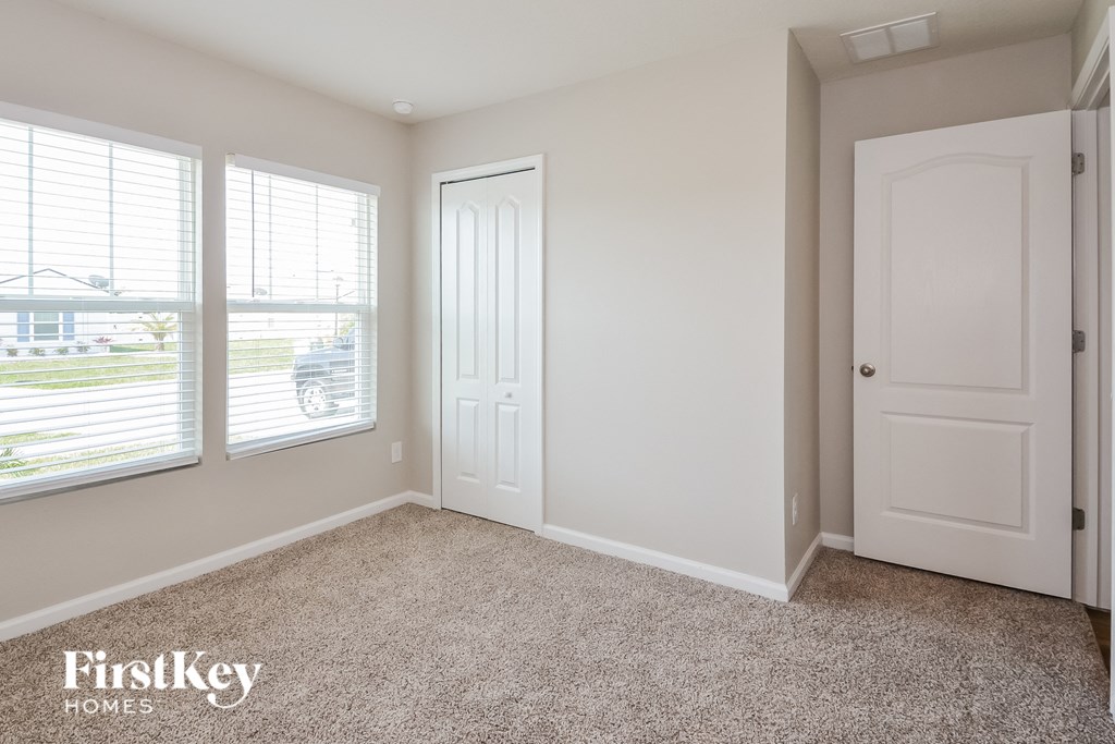 a bedroom with three windows and a door and a carpeted floor