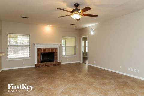 A spacious living room with a fireplace and a ceiling fan.