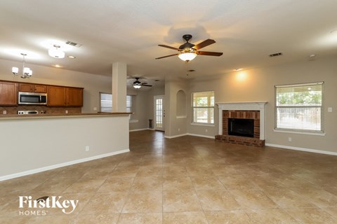 A spacious living room with a fireplace and a ceiling fan.