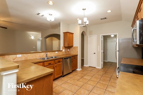 A kitchen with wooden cabinets and a tiled floor.