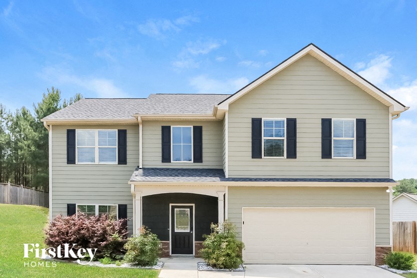 a tan house with black shutters and a white garage door