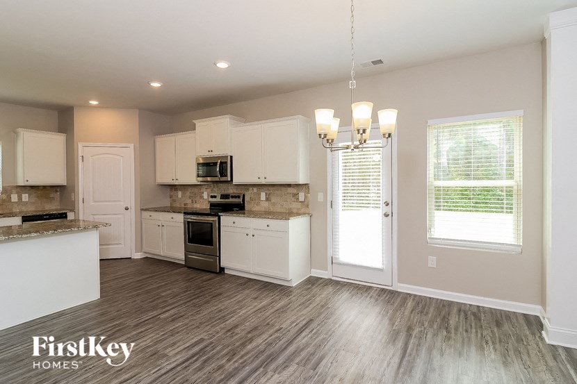 an empty kitchen with white cabinets and a window