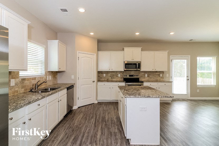 a large kitchen with white cabinets and marble counter tops