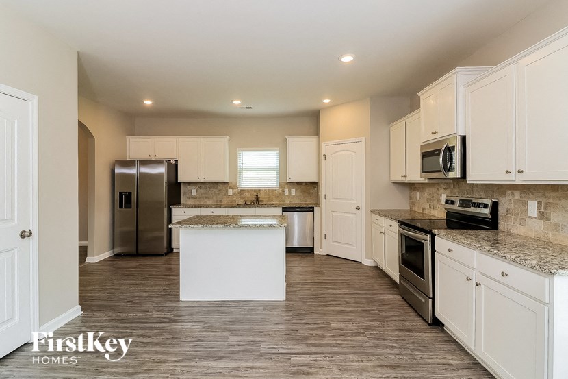 a large kitchen with white cabinets and stainless steel appliances