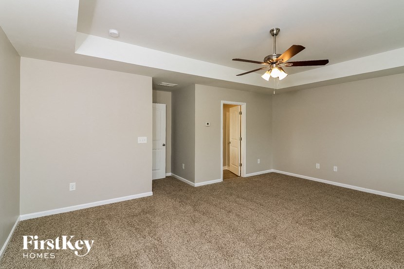 a living room with a ceiling fan and a carpet