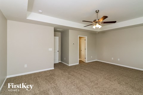 a living room with a ceiling fan and a carpet