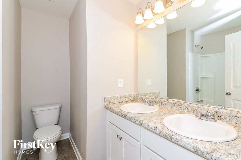 a bathroom with two sinks and a toilet and a mirror