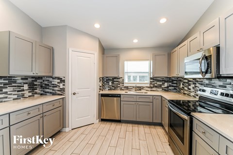 A kitchen with a tile floor and a stove top oven.