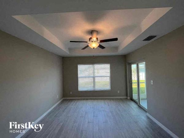 A room with a ceiling fan and sliding glass doors.