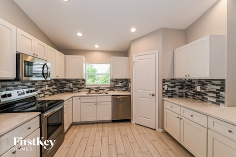 a kitchen with white cabinets and a stove and a sink