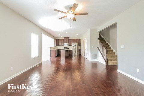 an open living room and kitchen with wood flooring and a ceiling fan