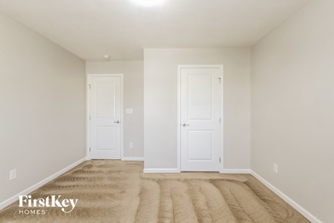 a bedroom with two doors and a carpeted floor