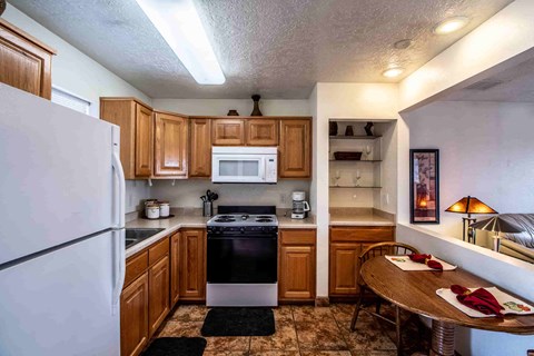a kitchen with wooden cabinets and appliances and a dining table