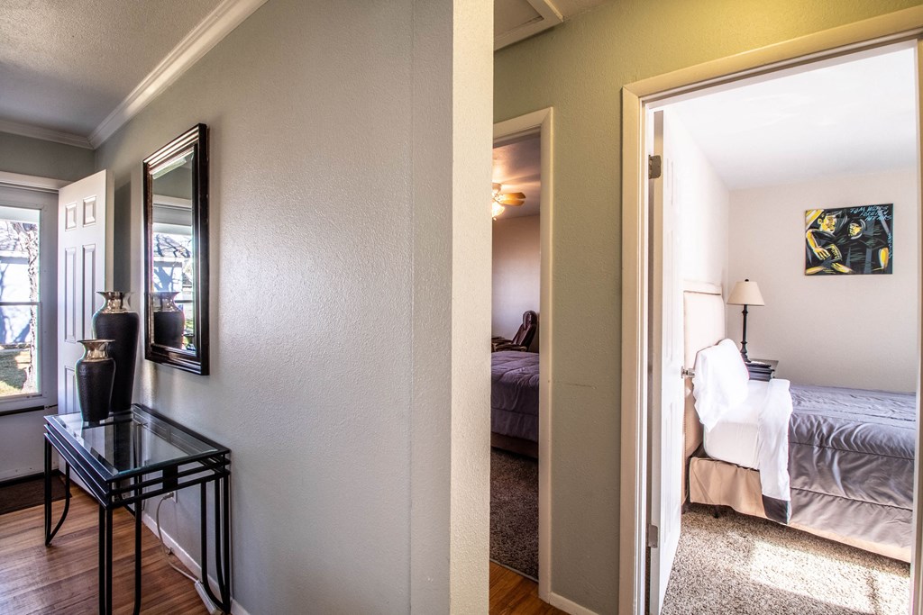 the view from the living room into the bedroom and the hallway to the bedroom closet