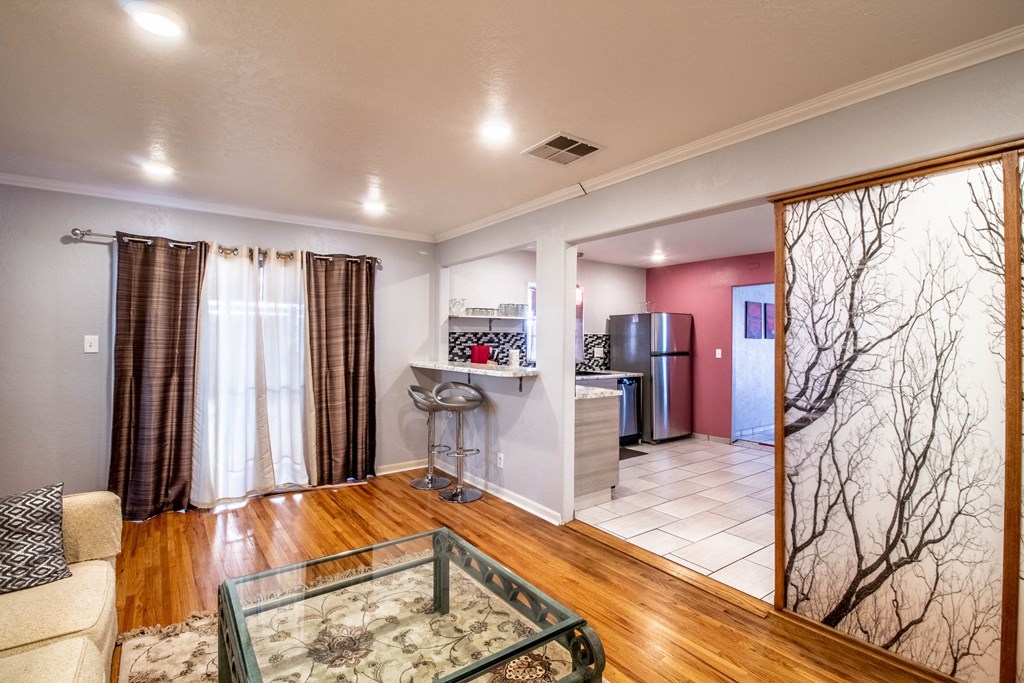 a living room with a glass table and a kitchen