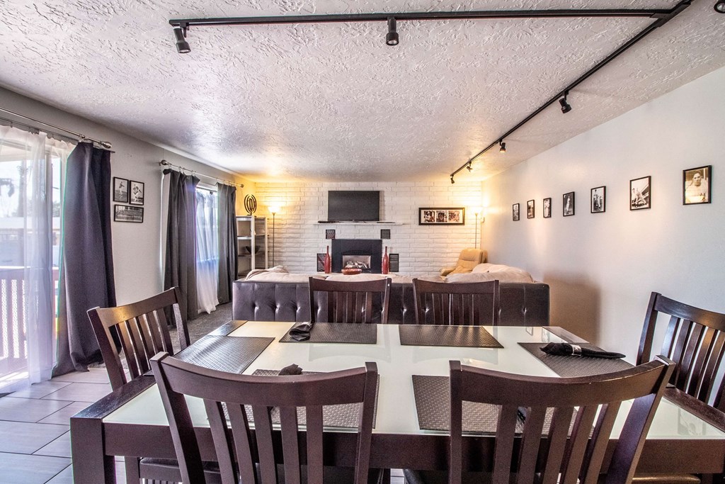 a dining room table with chairs and a living room with a fireplace
