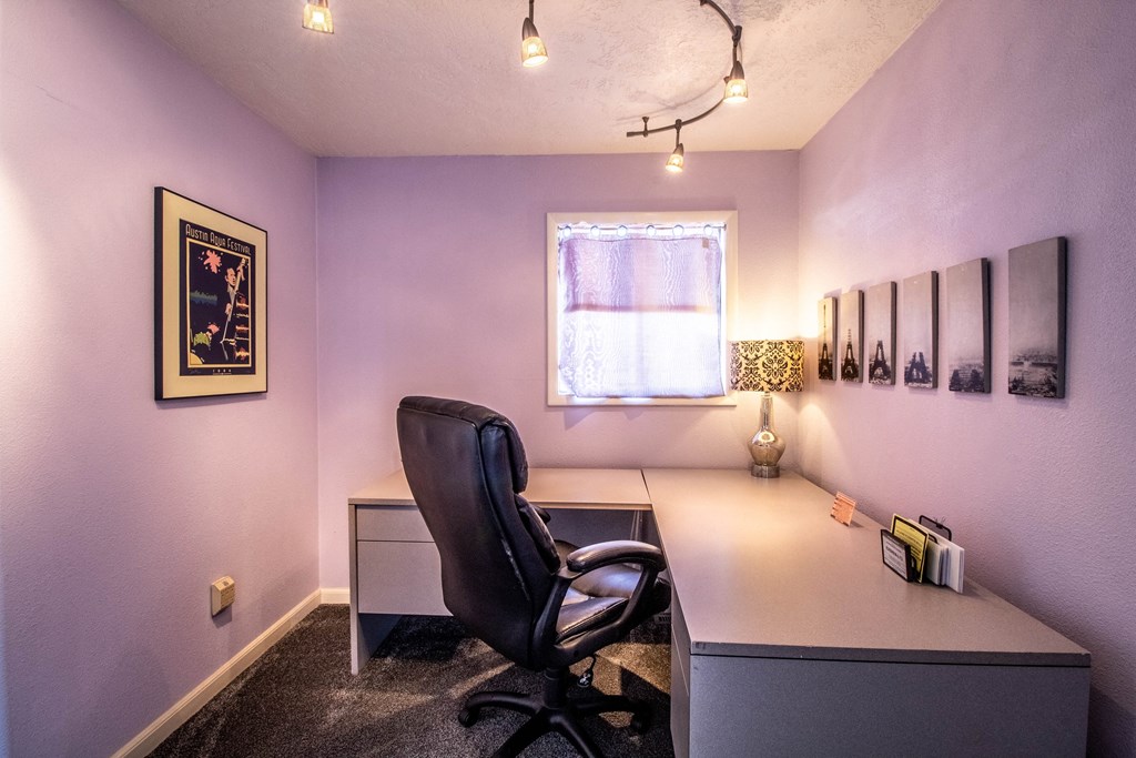 a home office with purple walls and a desk with a chair