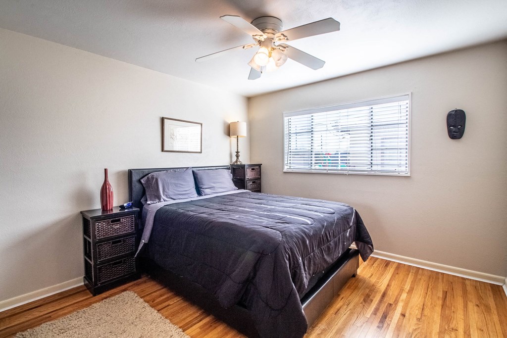 the master bedroom has a ceiling fan and a large bed